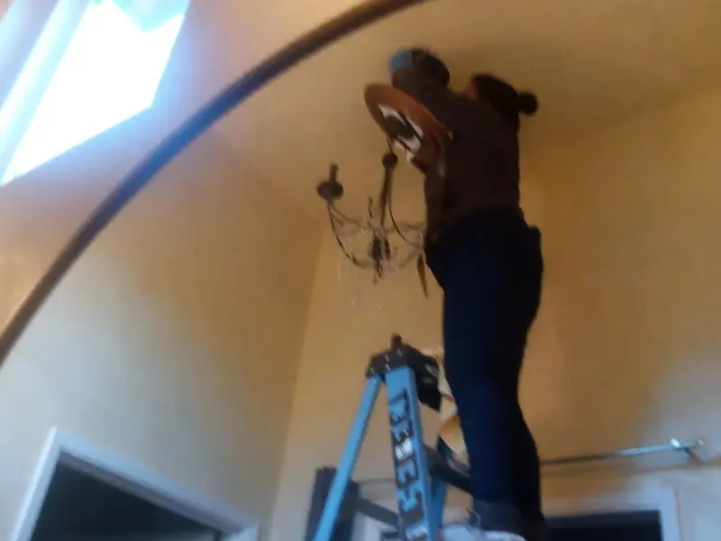Electrician installing a chandelier in a Eaton residence